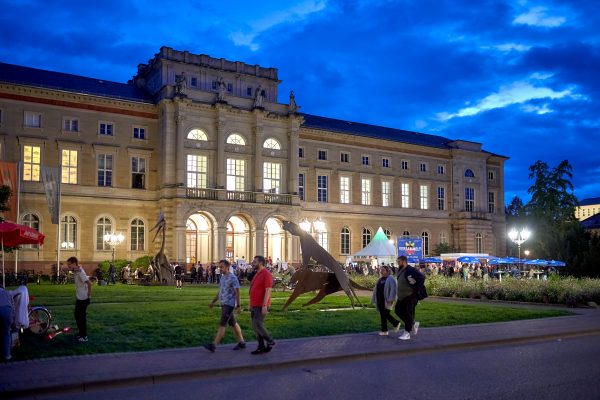 Naturkundemuseum bei Nacht von außen, viele Besucherinnen und Besucher davor