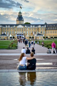Blic auf das Schloss Karlsruhe von außen, viele Menschen laufen auf den Eingang zu