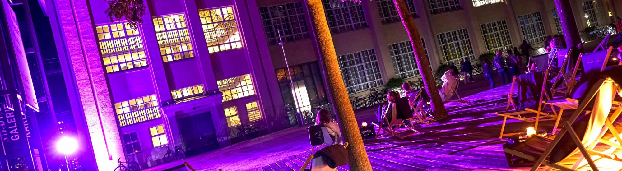 Strandstühle vor der Städtischen Galerie bei Nacht, auf Einigen liegen Besucher