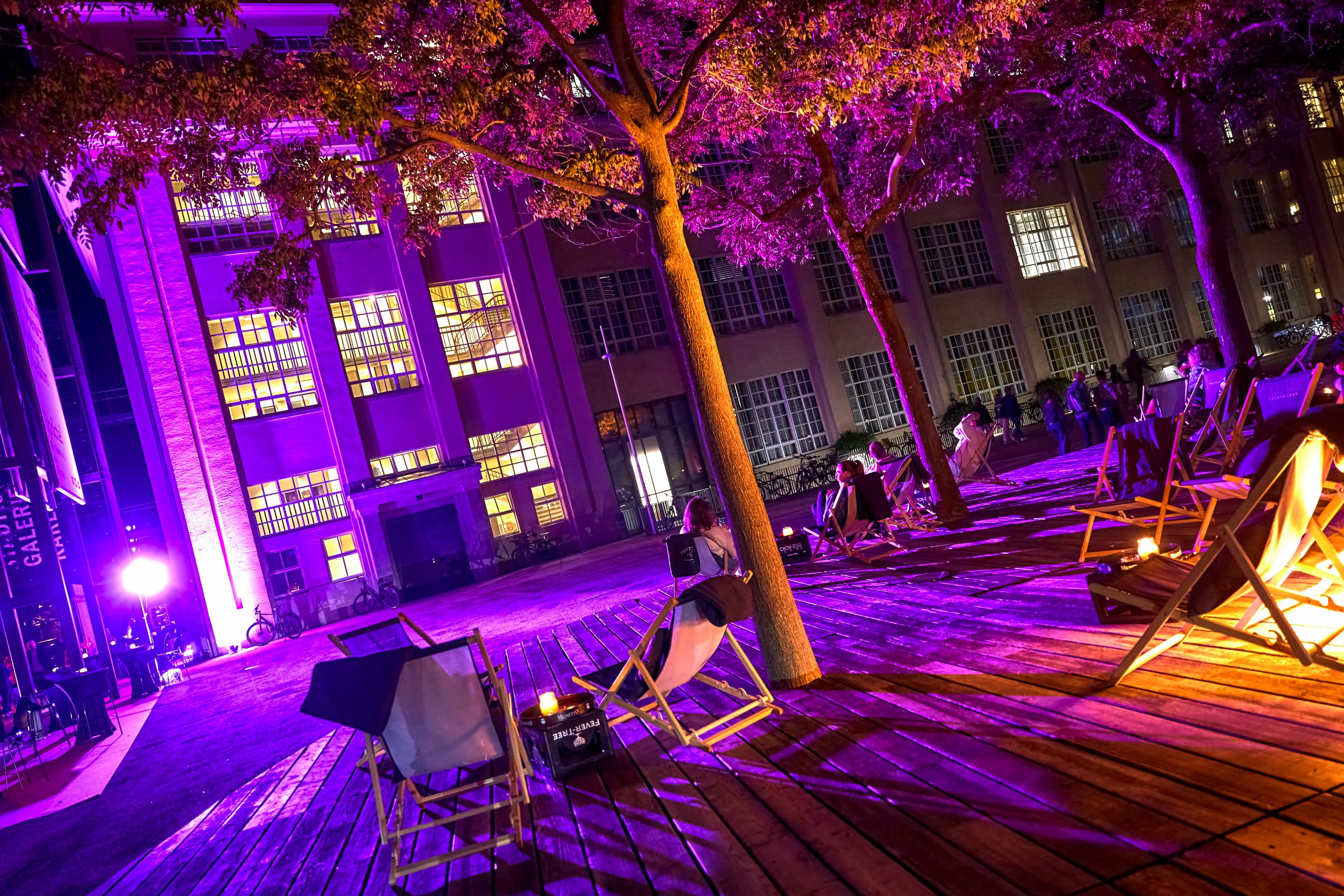 Strandstühle vor der Städtischen Galerie bei Nacht, auf Einigen liegen Besucher